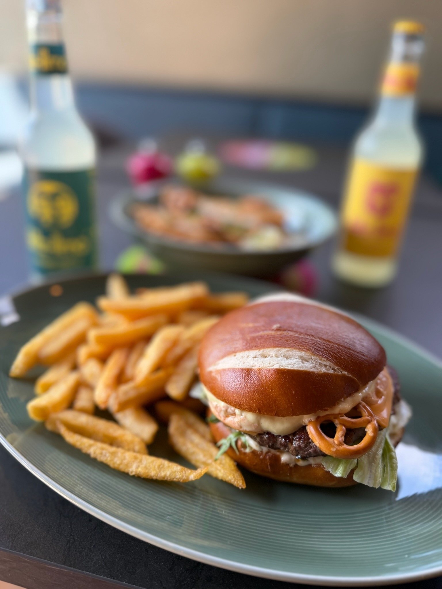 Burger im Laugenbun mit kleinen Brezeln, serviert mit Pommes
